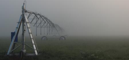 Irrigation water system in a green field in the dense fog.