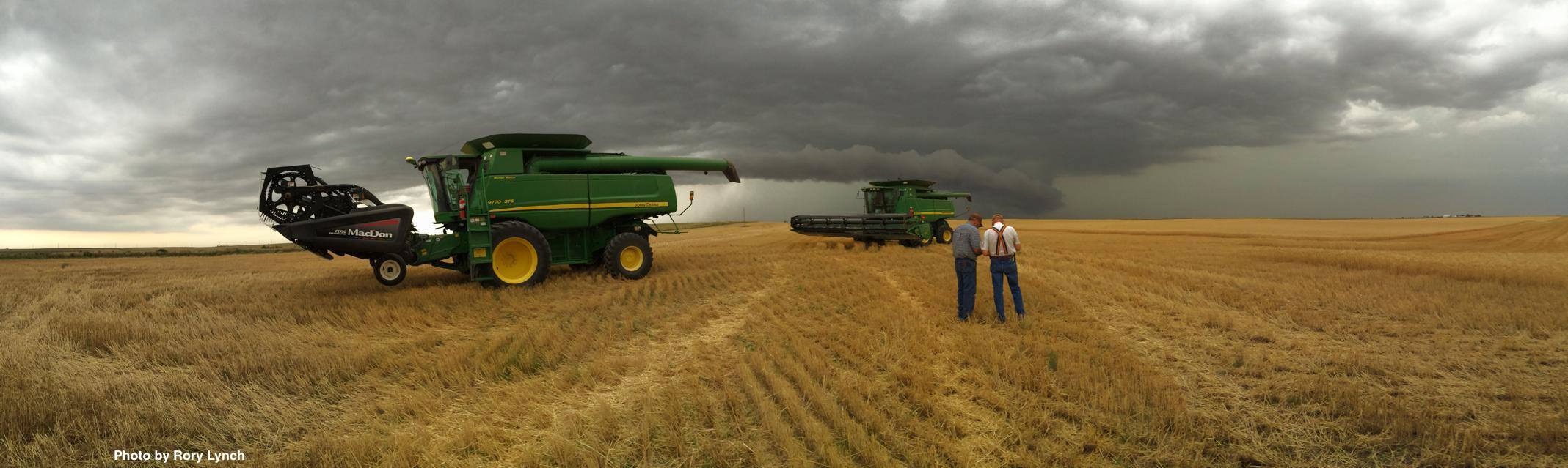 Two combines with two farmers in a thunderstorm