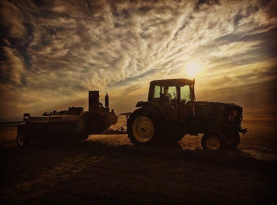 Tractor pulling equipment during cloudy sunrise