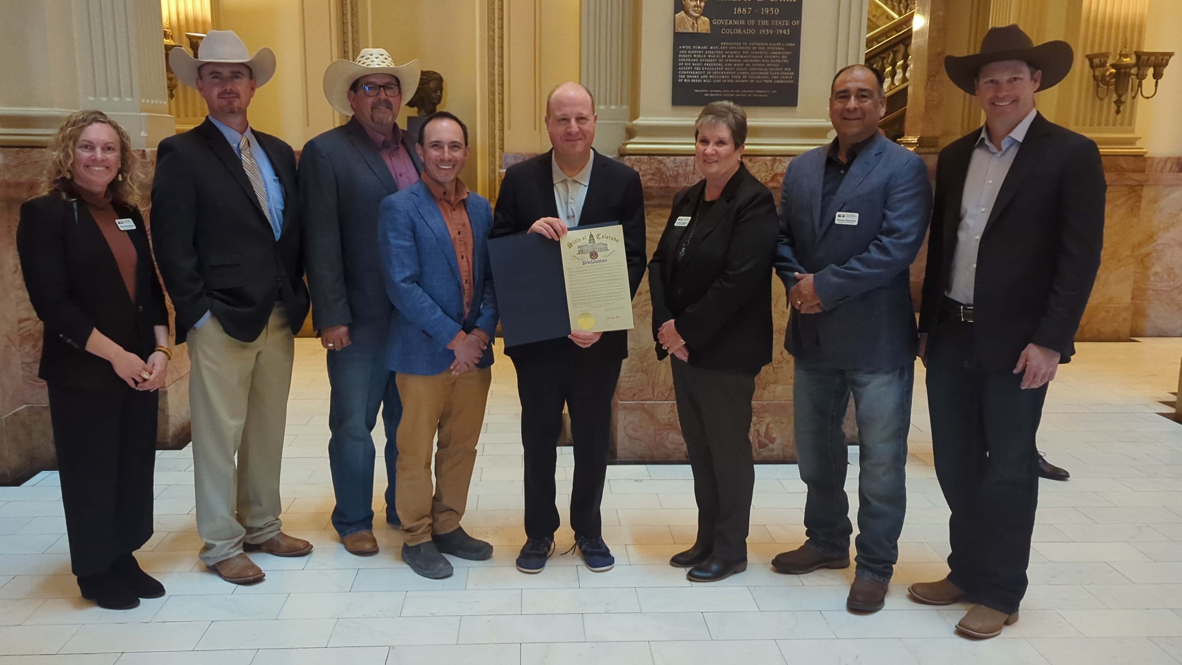 Commissioner of Agriculture Kate Greenberg and six members of the Colorado Ag Commission with Governor Jared Polis who holds the proclamation declaring March 20, 2024 as Colorado Ag Day