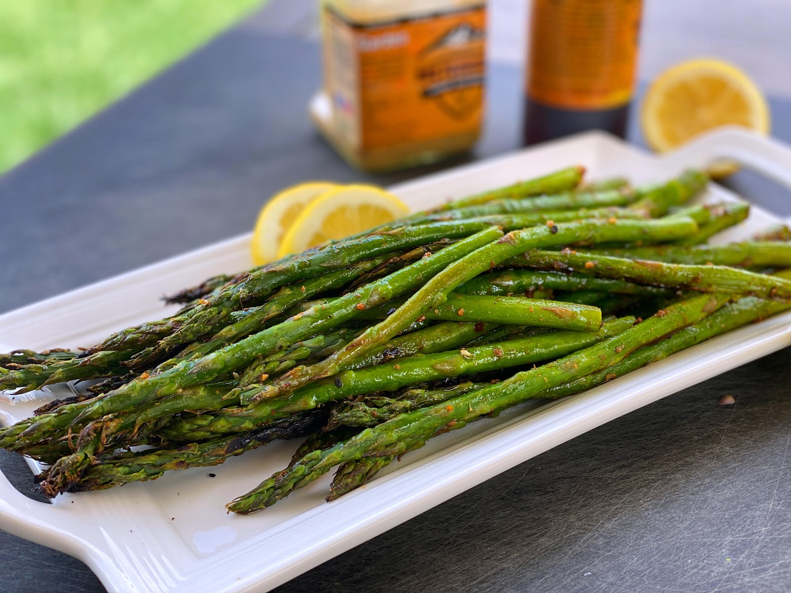 Grilled asparagus on a plate with wedges of lemon.