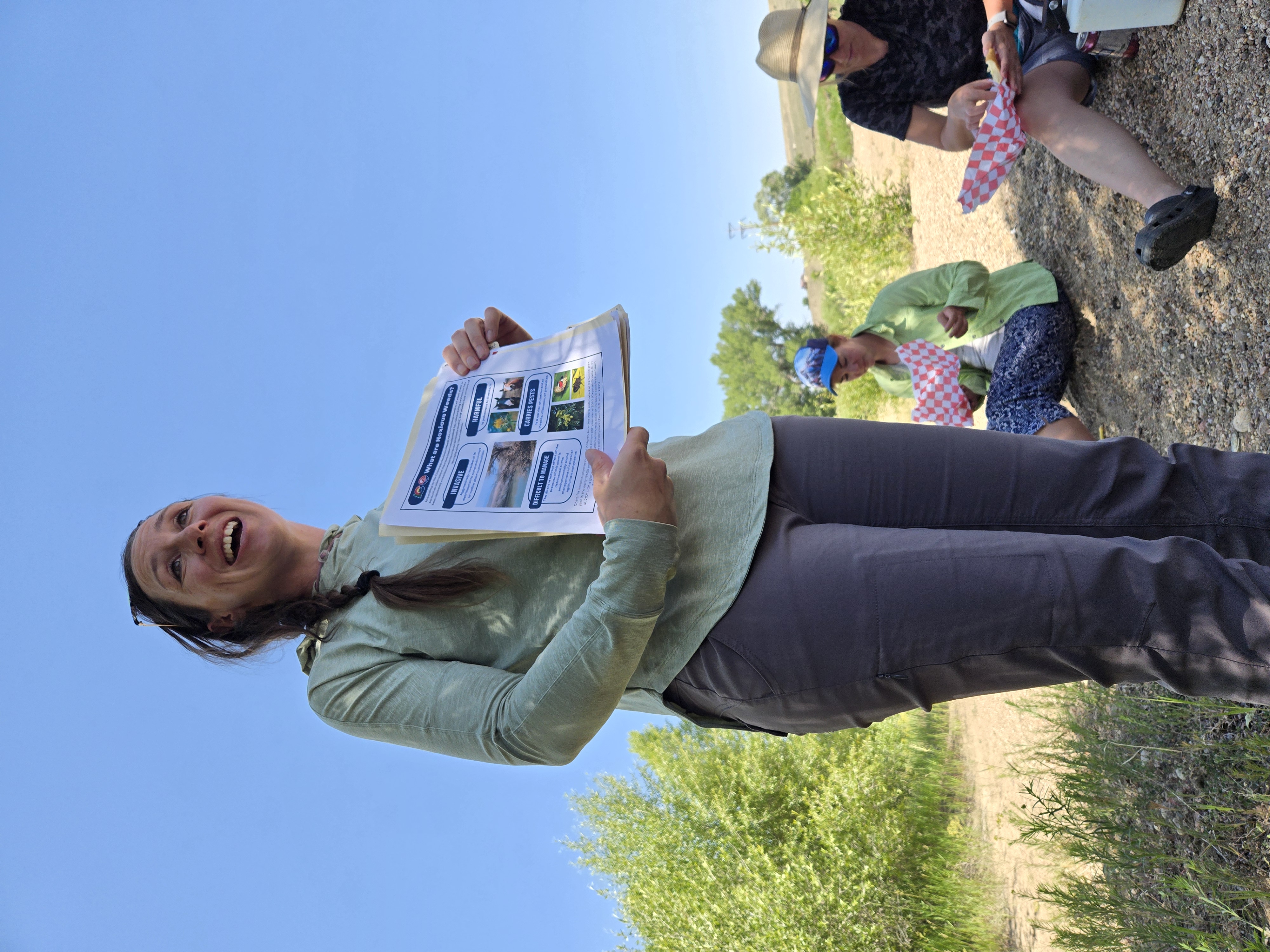 Palisade Insectary biologists Kristi Gladem holds up a flyer about noxious weeds