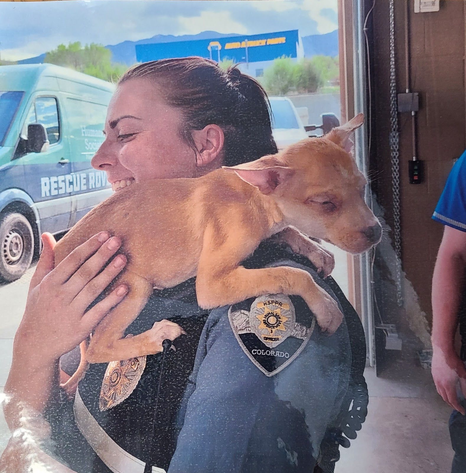 Smiling Kailie Barker holds a small dog over her shoulder