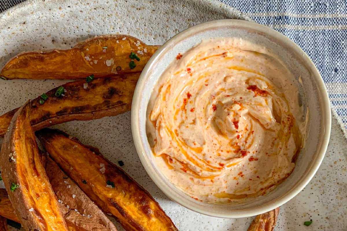 A bowl of creamy dip with a side of sweet potato steak fries