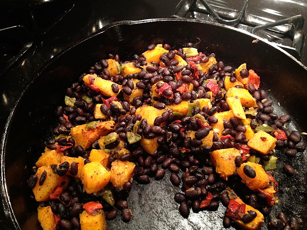 Butternut squash, black beans, and green chiles roasting in a cast iron skillet.