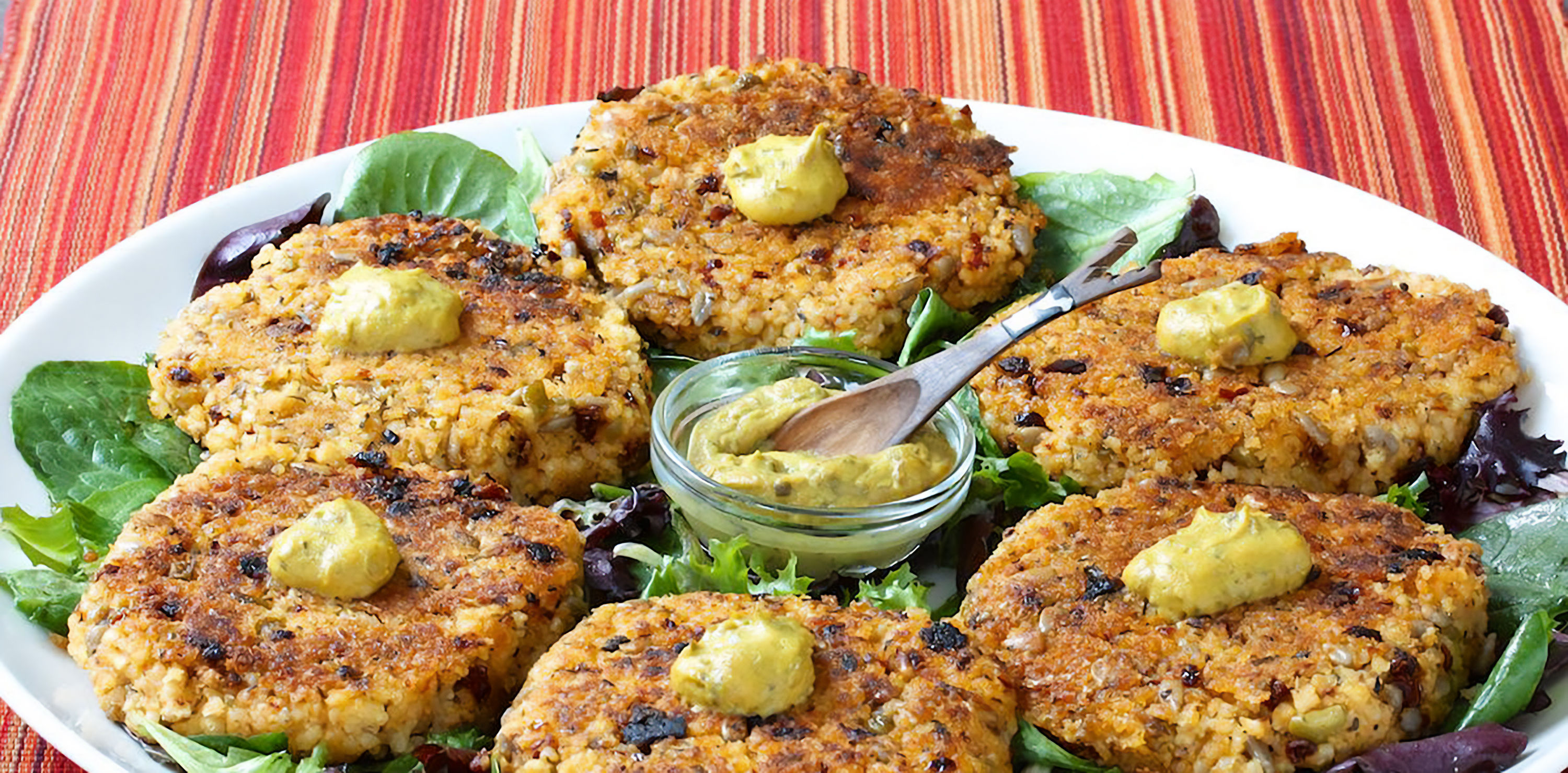 Millet cakes on a bed of vegetables, served with spicy mustard