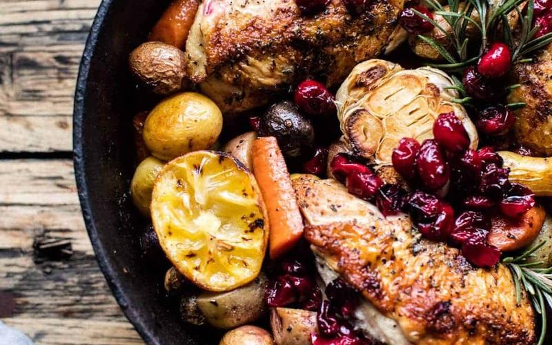 Cranberry Roasted Chicken with Potatoes, carrots, lemon and thyme in a cast iron skillet
