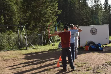Three students try out archery during Camp Rocky 2023