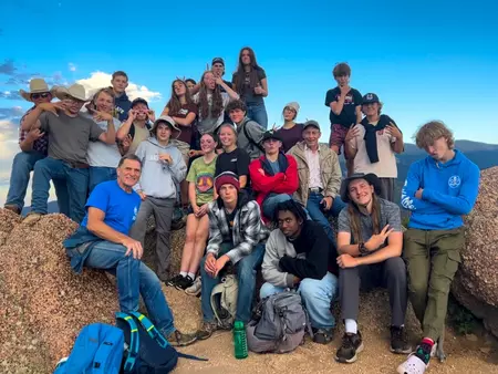 Group of Camp Rocky 2023 students posing on a mountain summit