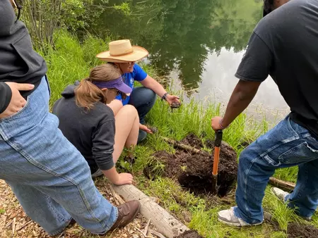 Students observe a soil sample test near a lake at Camp Rocky 2023