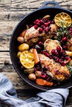 Cranberry Roasted Chicken with Potatoes, carrots, lemon and thyme in a cast iron skillet