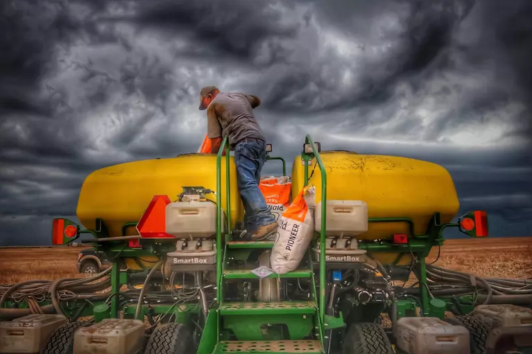 Man on a tractor in front of a dark cloudy sky
